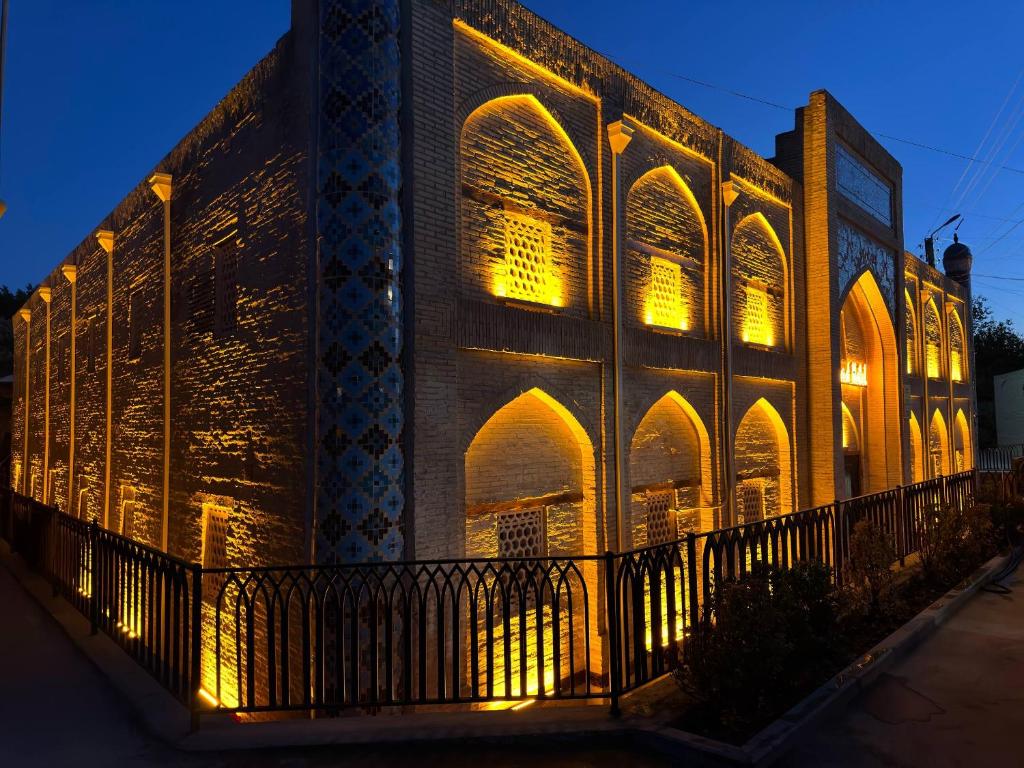 a large brick building with lights on it at Turkman Madrasah XIX Century Hotel in Bukhara