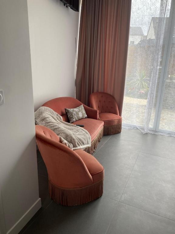 two chairs and a ottoman in a room with a window at Charmant petit maison in Pontorson