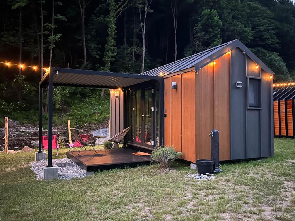 a small shed with a deck in a yard at night at Transfăgărășan River Retreat in Arefu