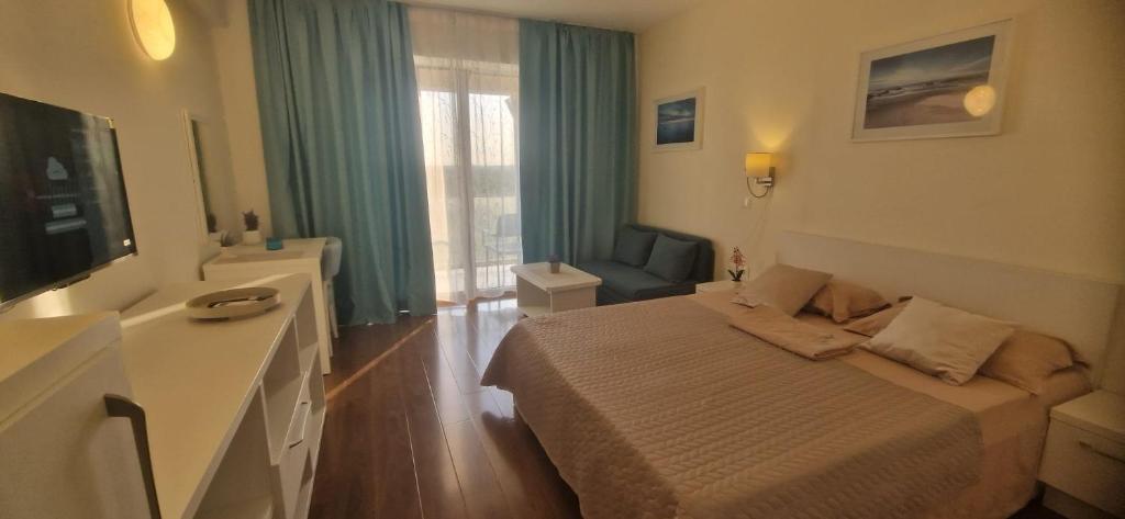a hotel room with a bed and a television at Adela Sunset View by Blaxy Resort in Olimp