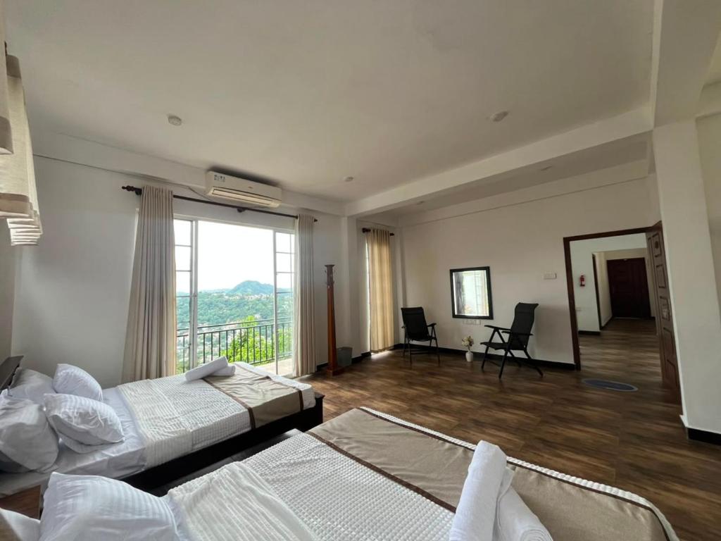 a bedroom with two beds and a large window at Sentinels Hotel Kandy in Kandy