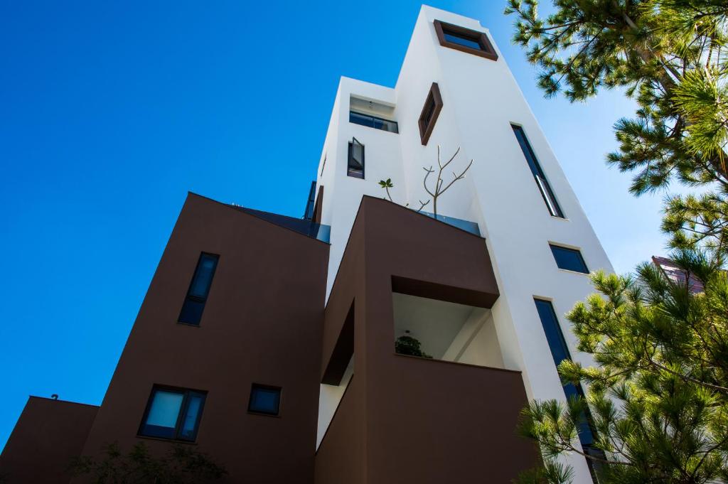 ein hohes weißes Gebäude mit Bäumen im Vordergrund in der Unterkunft Timia Homestay in Hualien