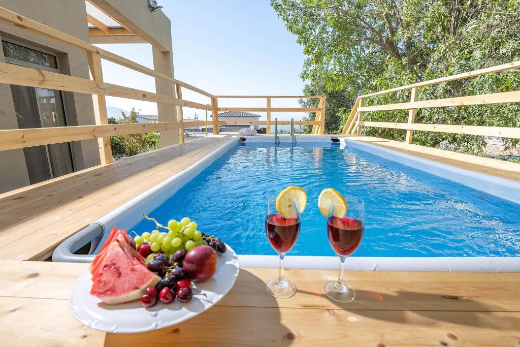 a plate of fruit and wine glasses next to a swimming pool at Me & U - הווילה שלי בכנרת in Tel Kazir