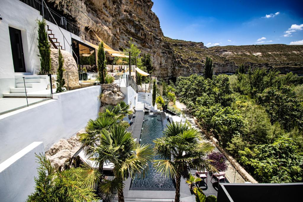 a resort with a pool with palm trees and a mountain at XUQ Hotels Lomas de Ruvira in Jorquera