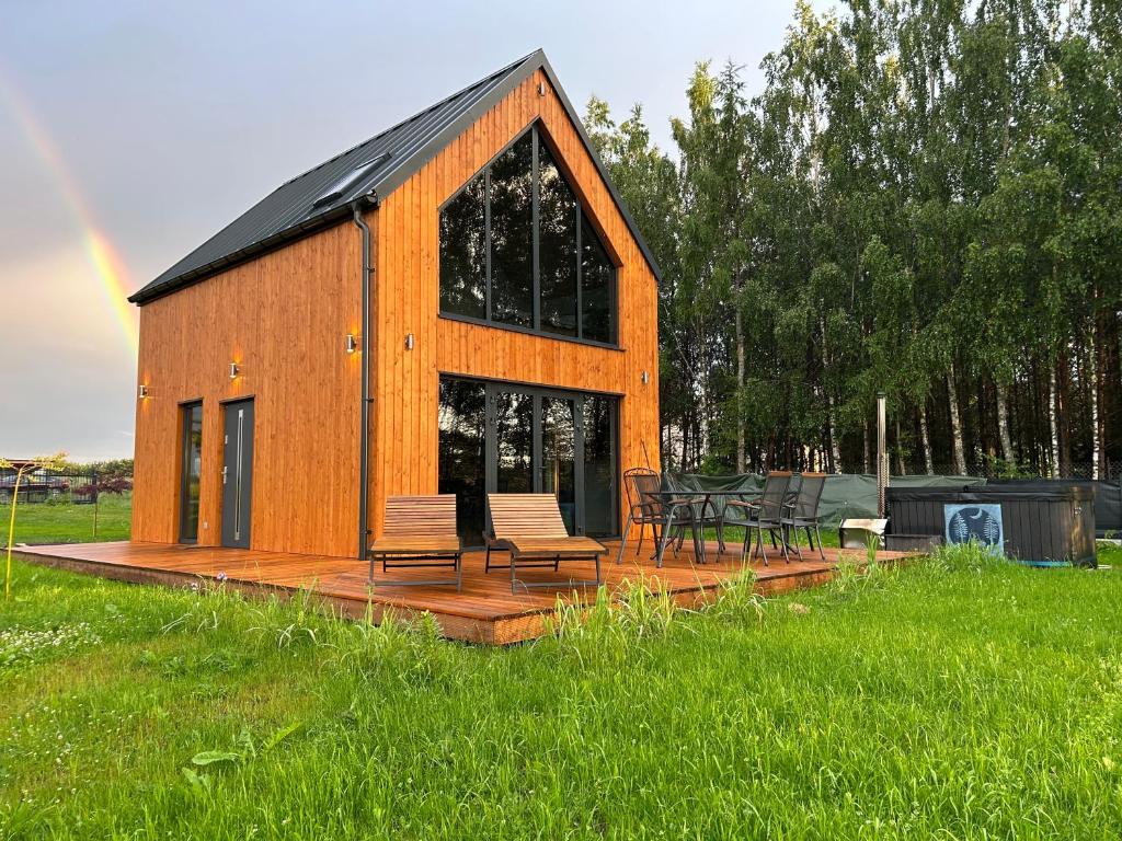 a wooden cabin with chairs and tables in a field at OAK House domek z balią w Serskim Lesie in Las Dalny
