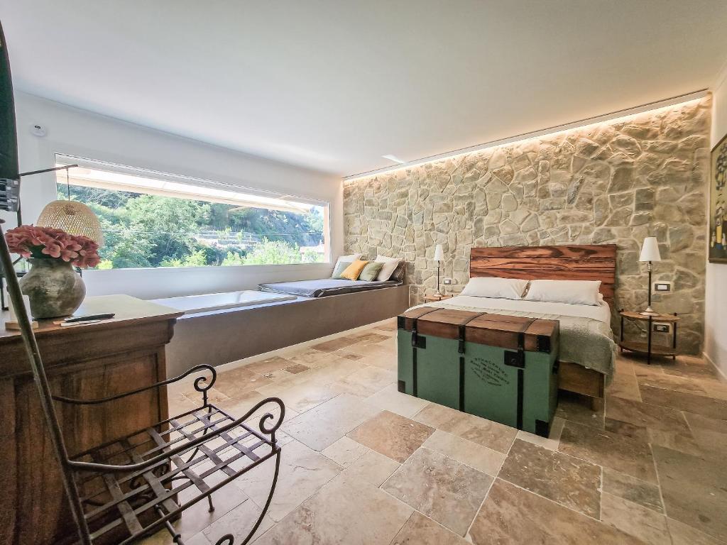 a bedroom with a bed and a stone wall at Bona A Vui Rooms in Soldano