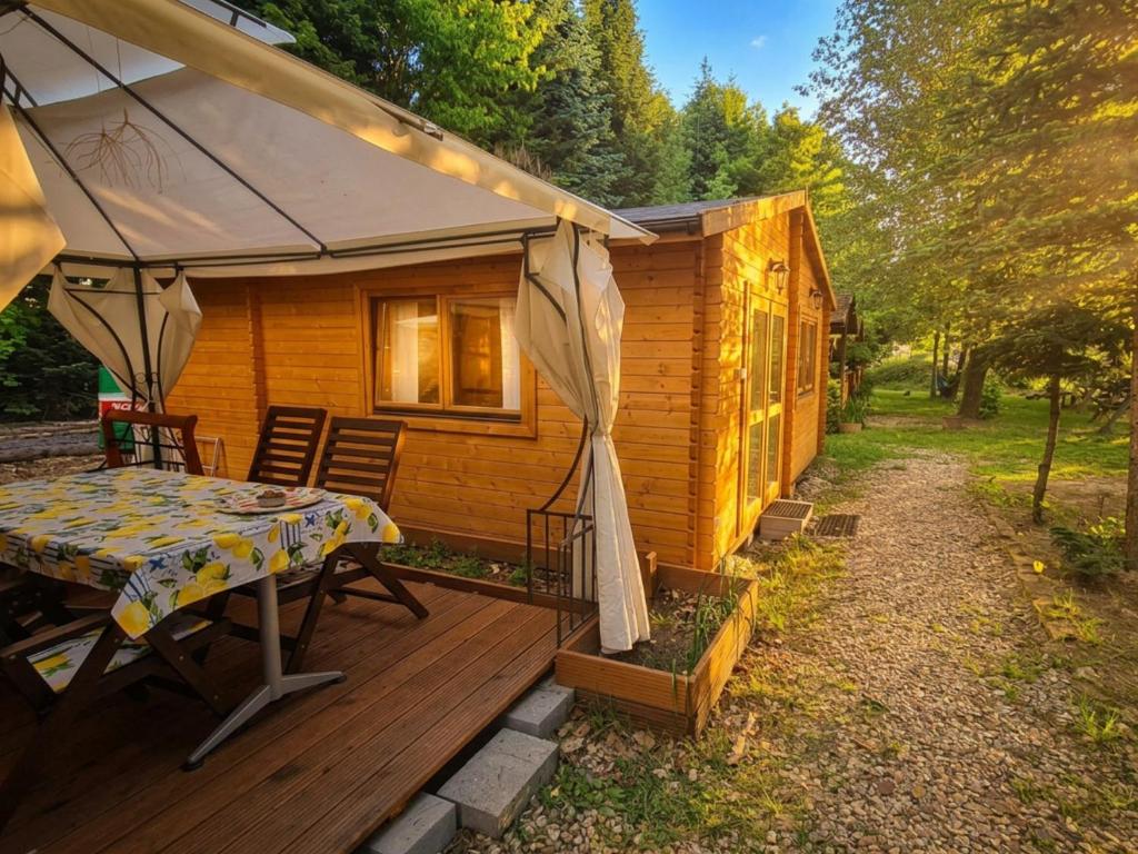 a wooden deck with a table and an umbrella at Pensjonacik Ogrody in Pierzchno