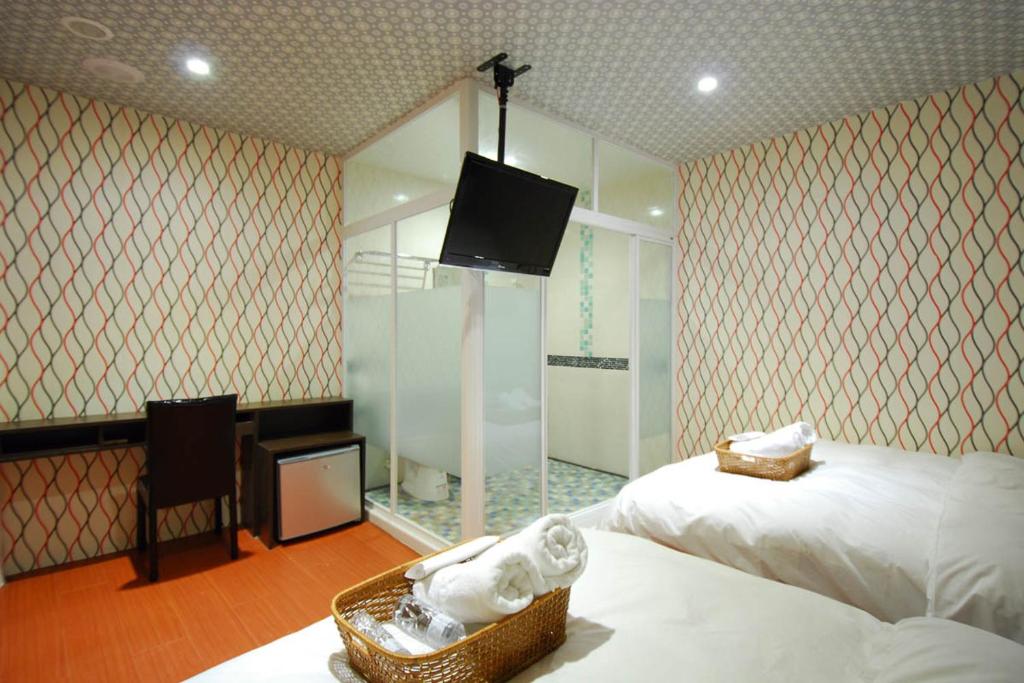 a hotel room with two beds and a tv and a room at Happiness Inn in Taipei