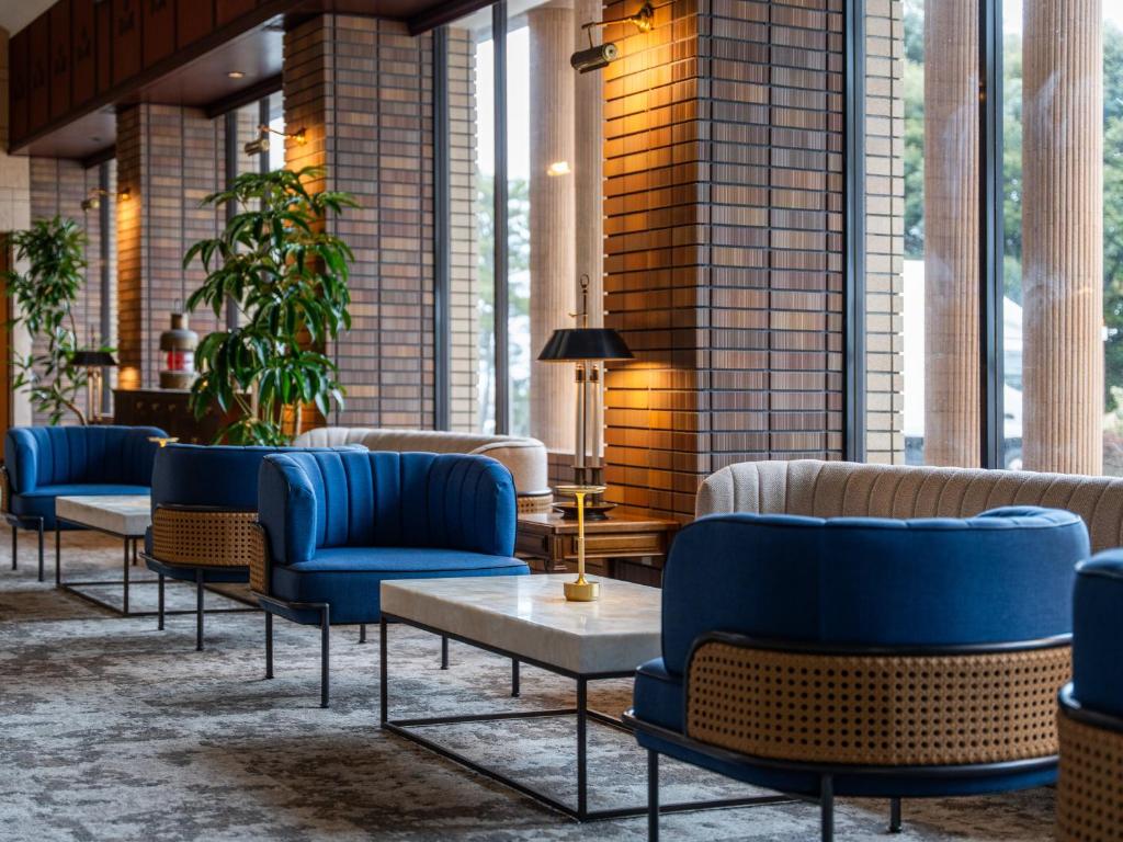 a lobby with blue chairs and tables and windows at Oarai Park Hotel in Oarai