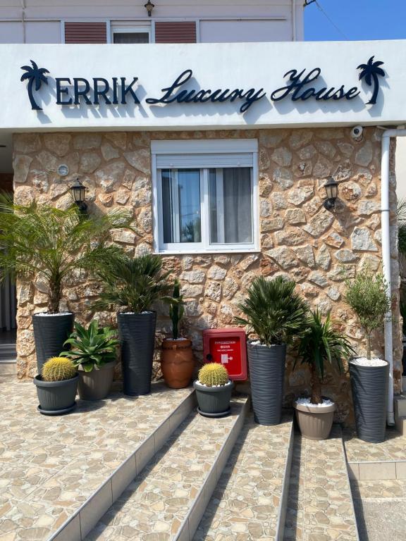 a restaurant with potted plants in front of a stone building at Errik Luxury House in Faliraki