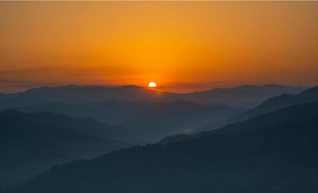 a view of the sun rising over a mountain range at The Kalindi's Resort, Almora in Almora