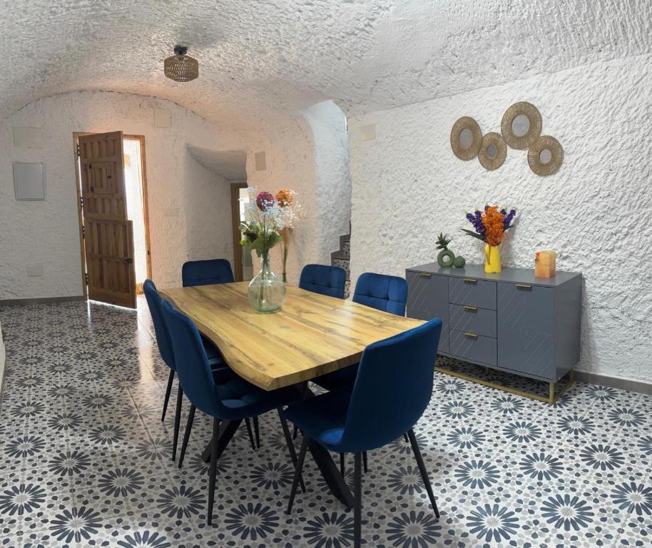 a dining room with a wooden table and blue chairs at Cueva Pilar in Graena