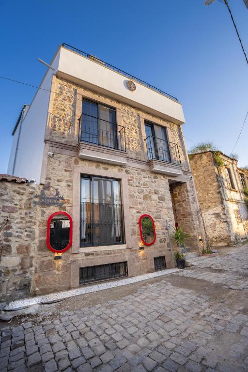 a stone building with red windows on a street at Shire Küçükköy in Ayvalık