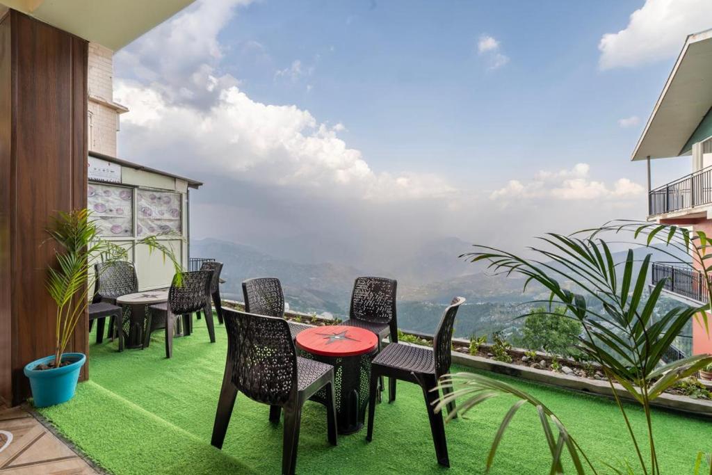 a patio with chairs and tables on a balcony at Valley Vista Rooms l Restaurant and Cafe l Forest Treks l Kufri by Exotic Stays in Kūfrī