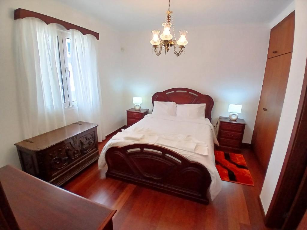 a bedroom with a large bed and a chandelier at Lúcia's House in Santa Cruz