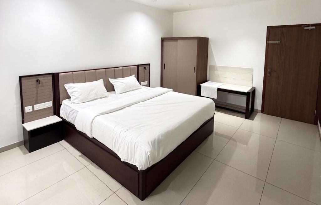 a bedroom with a large bed and a night stand at Bala Saraswathi Residency in Tuticorin