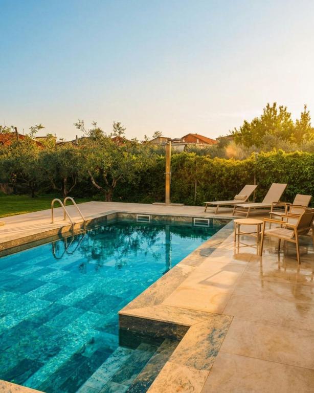 a swimming pool with a table and chairs next to it at Zeusplace Magic Pool Villa in Aigínion
