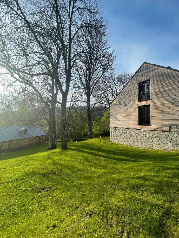 a building in a field with a tree and a building at Apartman Jasan Spot in Železná Ruda