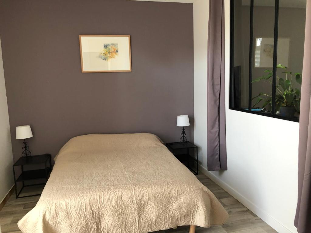 a bedroom with a bed and two tables with lamps at Le Logis du GAST Chambre Taupe in Le Gast