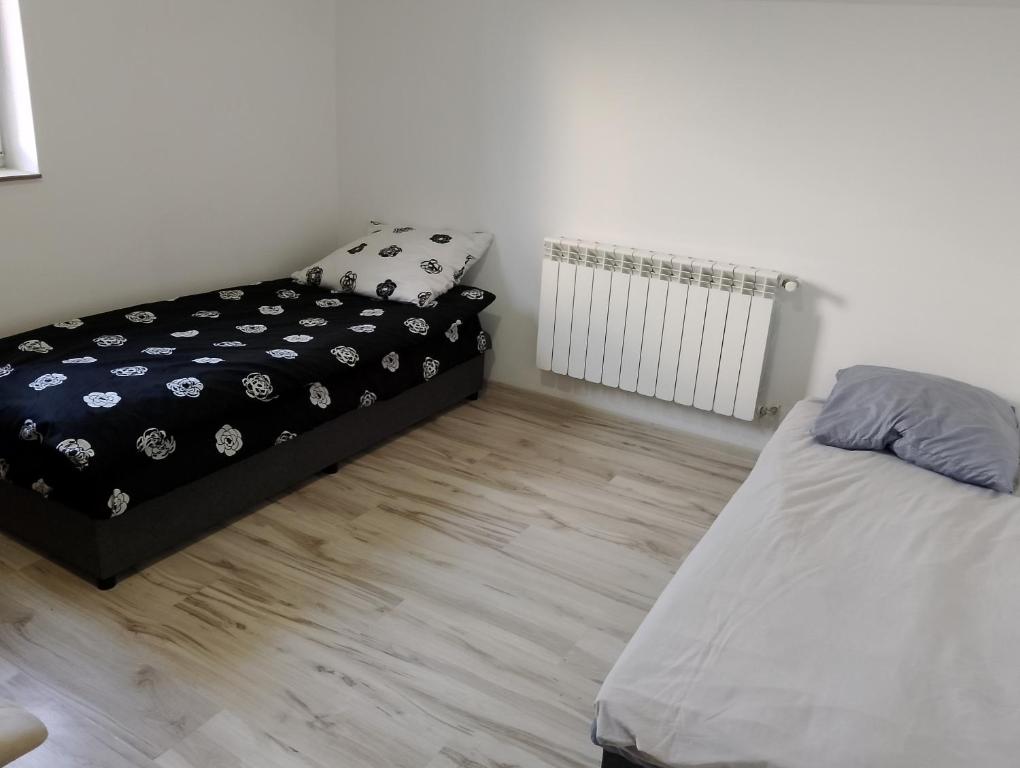 a bedroom with two beds and a radiator at Hostel Pod Lasem in Altanka