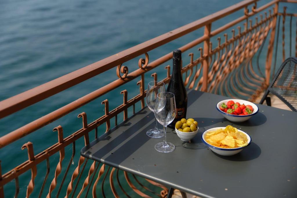 a table with two glasses and bowls of food and wine at Grace Suite with Jacuzzi Wonderful Lakefront View in Colonno