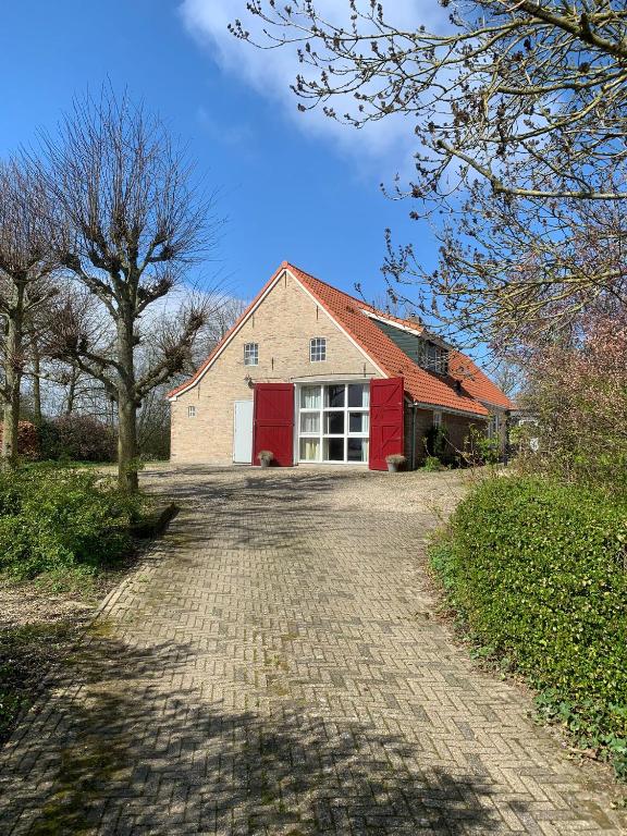 a brick road leading to a red house at B & B it Heech in Ferwerd