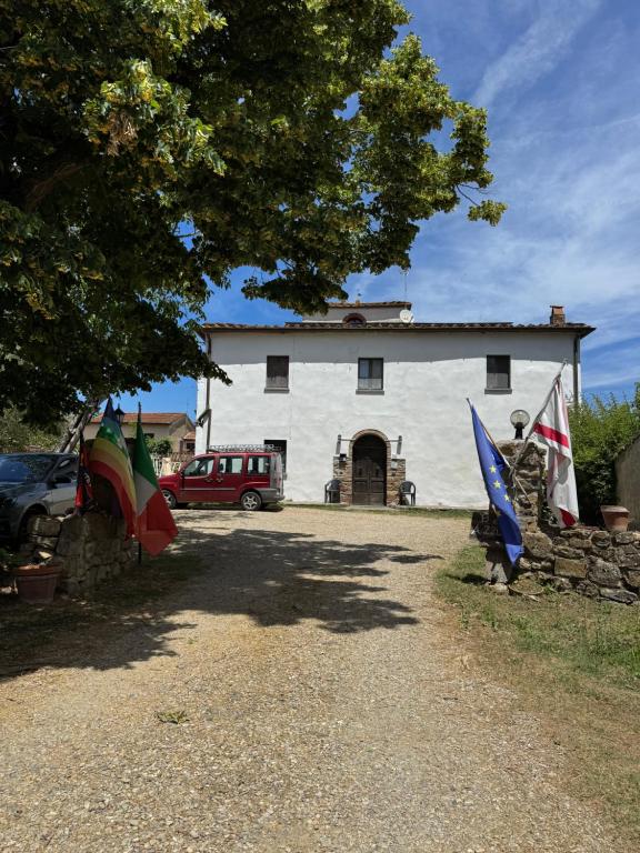 ein weißes Gebäude mit Flaggen davor in der Unterkunft Azzurre BeB in Laterina