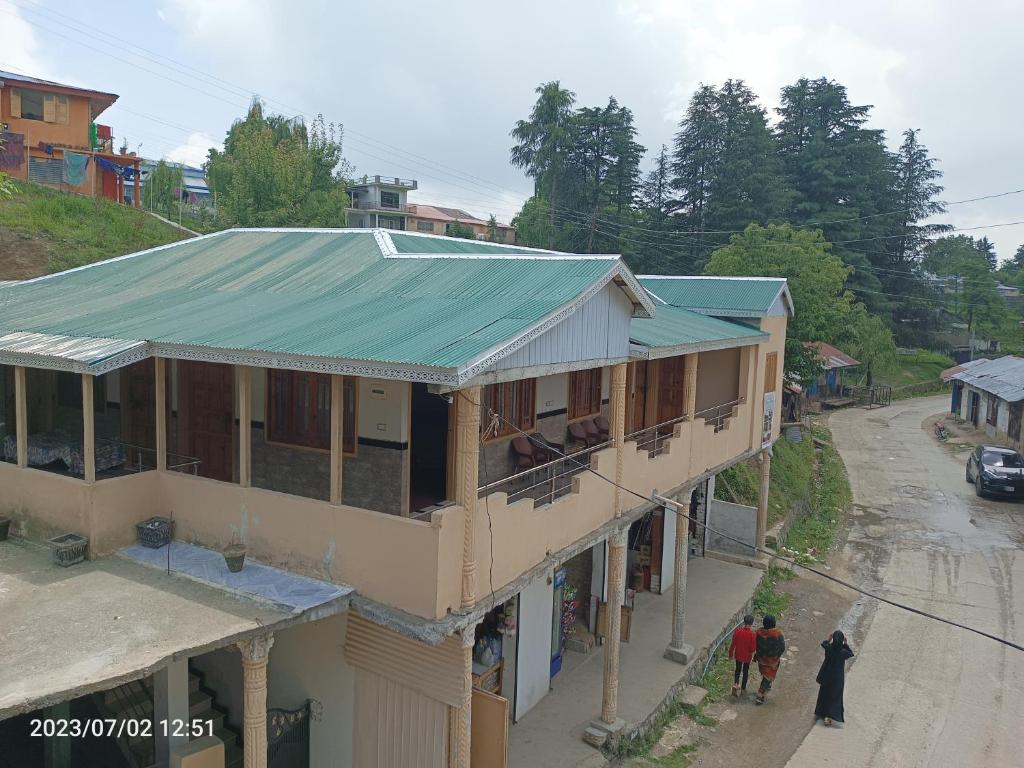 a building with a green tin roof on a street at ViveGee Cottage Khanipur Ayubia in Ayubia