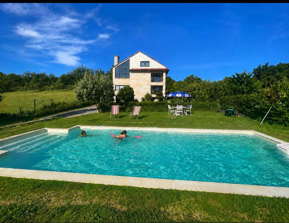 a person in a swimming pool in front of a house at CASA Arce in Boqueijón