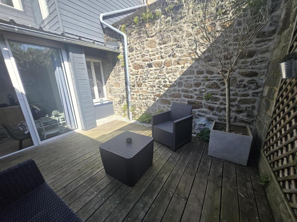 a patio with two chairs and a table and a tree at 2 Pause détente avec terrasse privée in Ernée