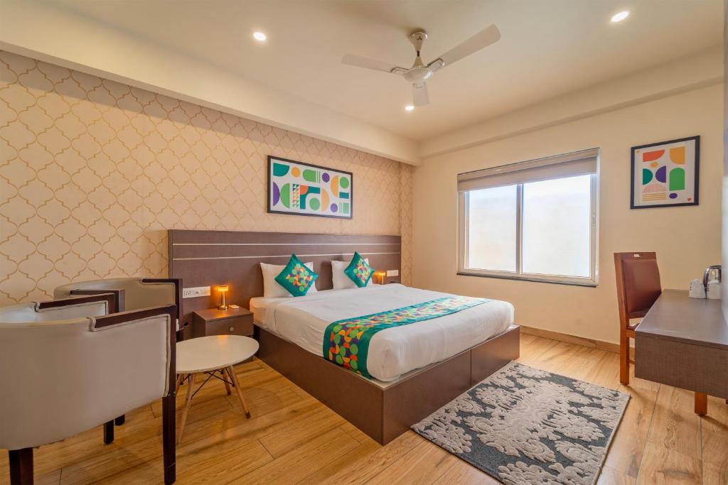 a bedroom with a bed and a table and a desk at Treebo Premium Lavender Kochi Infopark in Cochin
