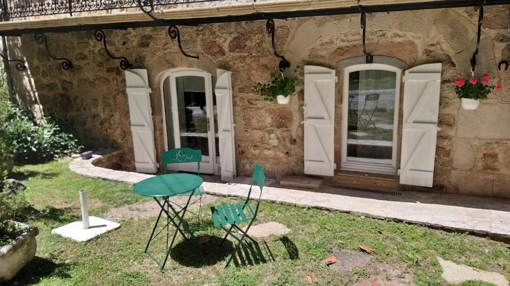 a house with two chairs and a table in the yard at La chambre d'hôtes du moulin de Vignars in Ginals