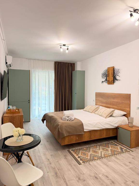 a bedroom with a large bed and a table at Apartament Căciulata Duo cu 2 camere independente in Căciulata