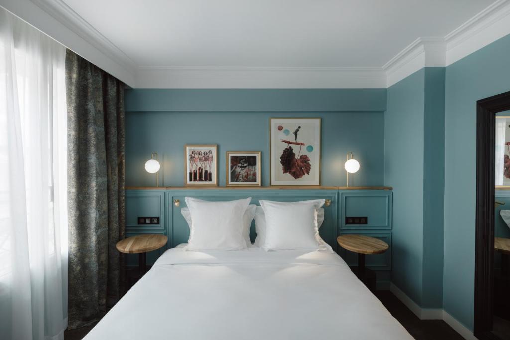 a bedroom with a large bed with blue walls at XO Hotel Paris in Paris