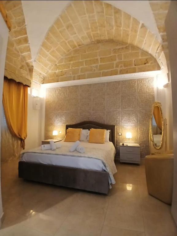 a bedroom with a large bed with a stone wall at B&B I like salento in Uggiano la Chiesa