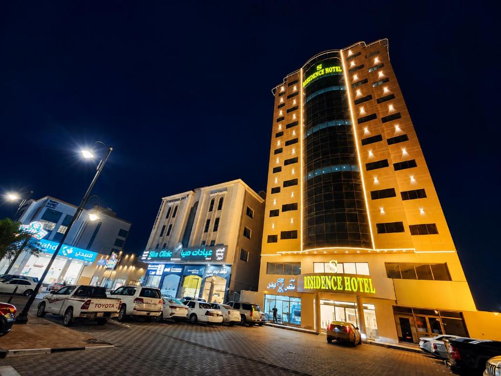 a building with cars parked in a parking lot at night at S Maskan in Dammam