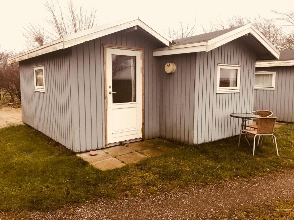 ein kleiner Schuppen mit einer weißen Tür und einem Tisch in der Unterkunft Ore Strandcamping in Vordingborg