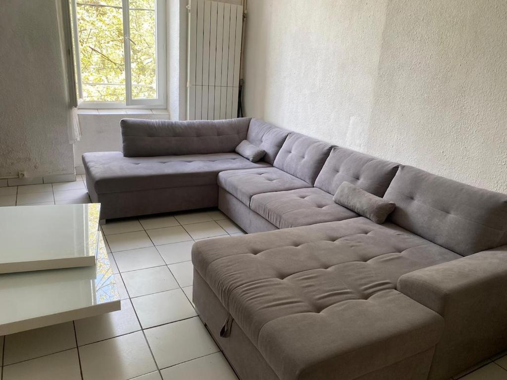 a living room with a couch and a table at Le cadeau bleu, duplex en Cévennes in La GrandʼCombe