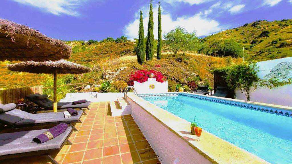 a pool with umbrellas and chairs next to a mountain at Cortijo Lagar de Luisa in Borge