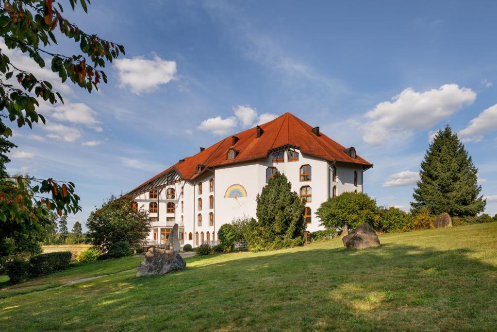 a house with a red roof on a green field at Leonardo Med Spa Resort in Nondorf