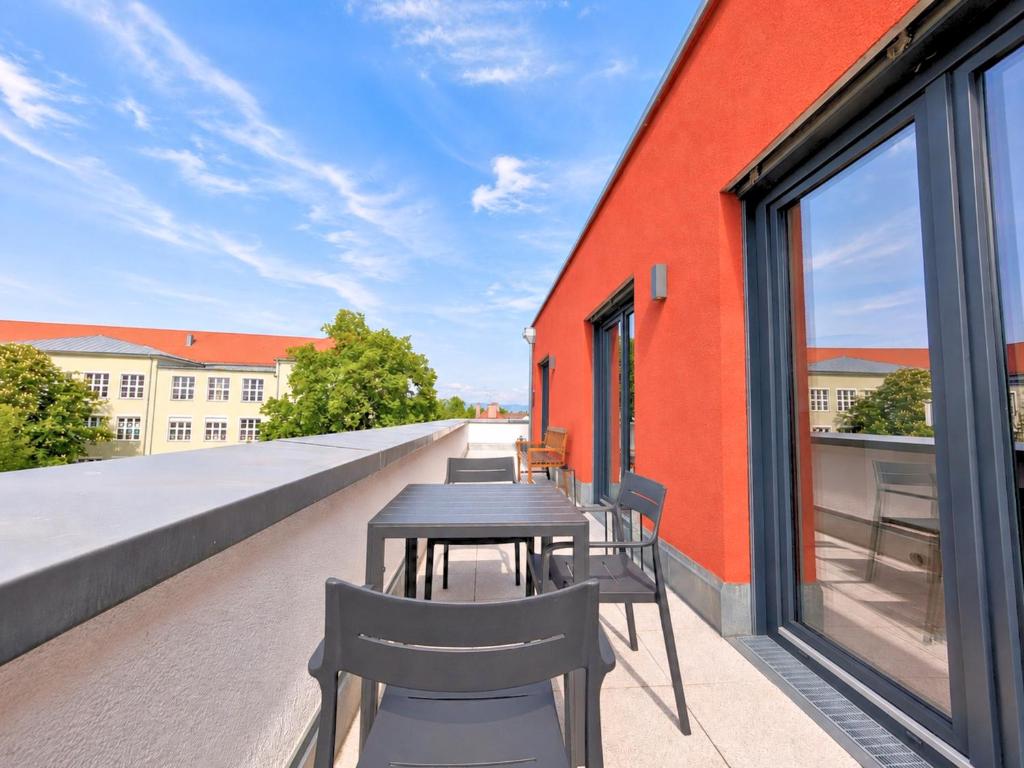 a balcony with tables and chairs on a building at Fynbos City Penthouse, Dachterrasse, Design-Küche, Parkplatz in Straubing