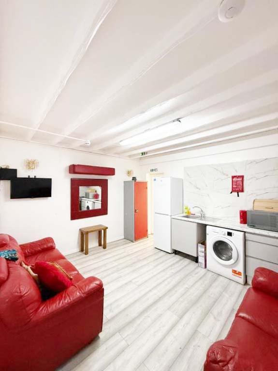 a living room with a red couch and a kitchen at Park View in Goodmayes