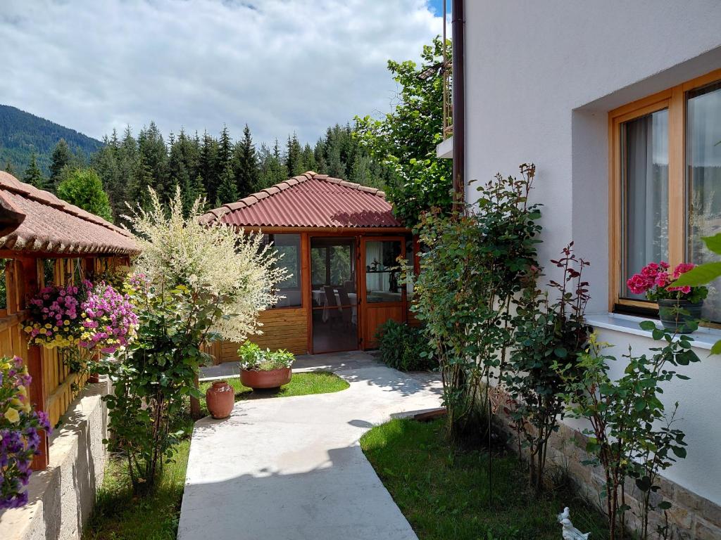 a house with a garden with flowers in front of it at Guest House Stoletnika in Yagodina
