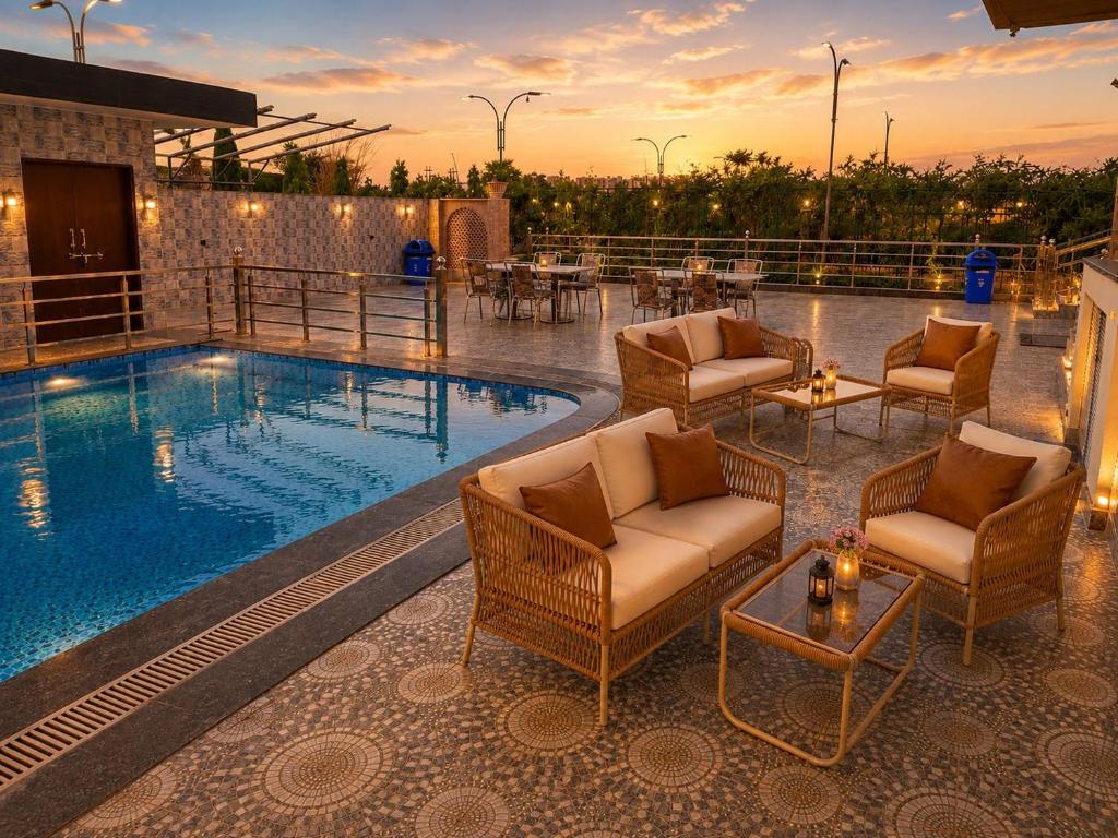 a resort pool with chairs and a table and a table at Vianara's Eco Feel Resort in Jaipur