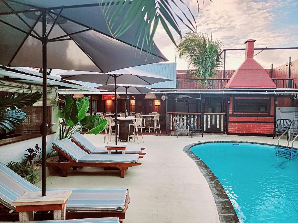 a pool with chairs and umbrellas next to a building at TRR3 Apt near Beach with Fine Cuisine & Pool in Grand-Baie