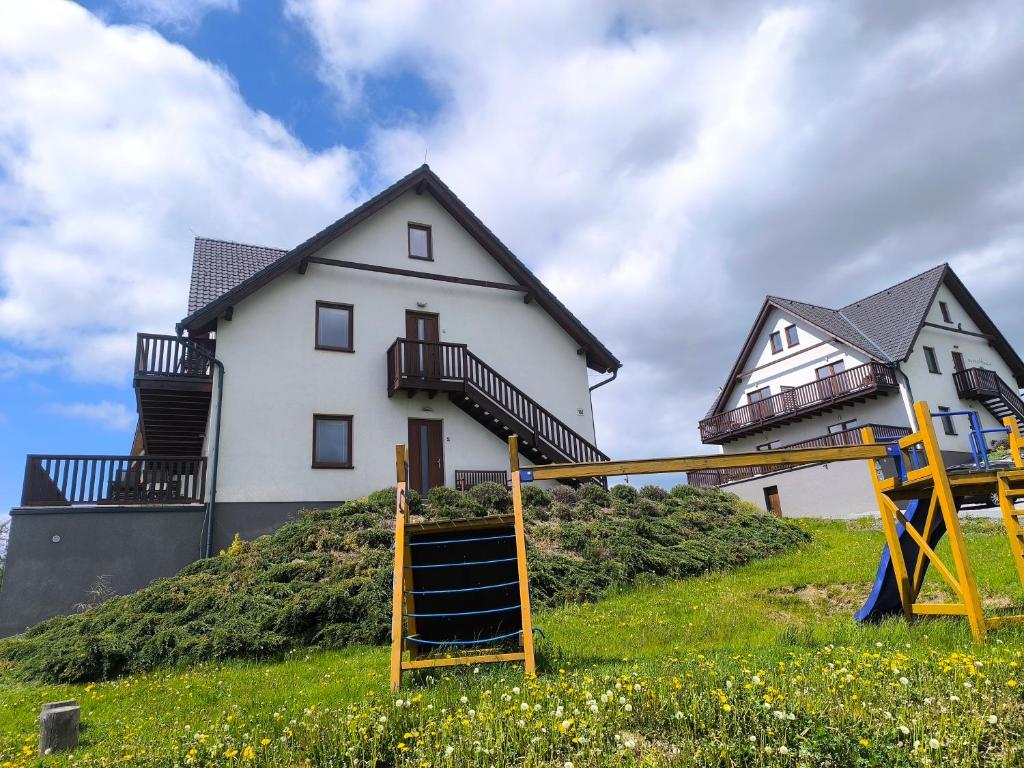 a house on top of a hill with a playground at Horský apartmán U Čerťáka in Horní Václavov