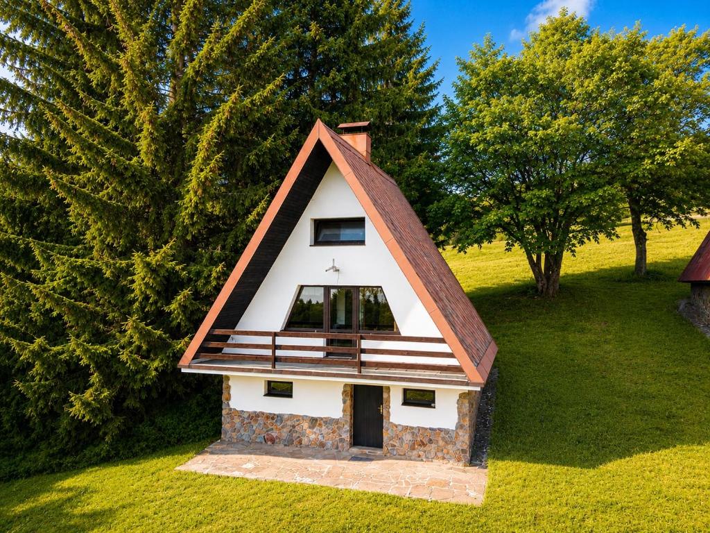 a small house with a steep roof on a field at Chata pod Černou horou in Rudník