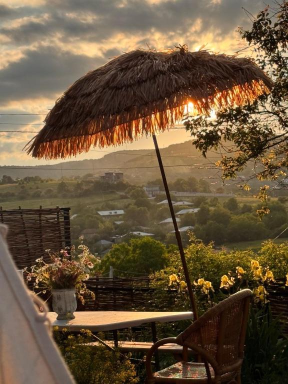 a table with a straw umbrella and a table and chairs at Dusheti Retreat - Authentic Georgian Living in Dushetʼi