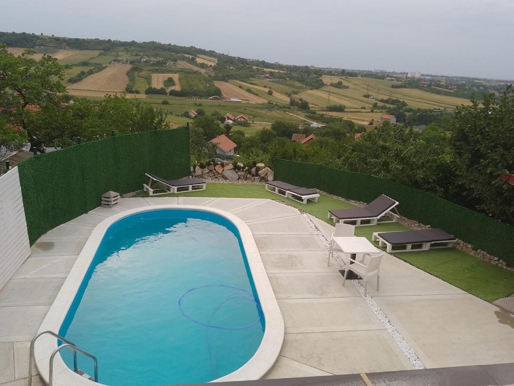 a swimming pool on a patio with two benches at Green View in Petrovaradin