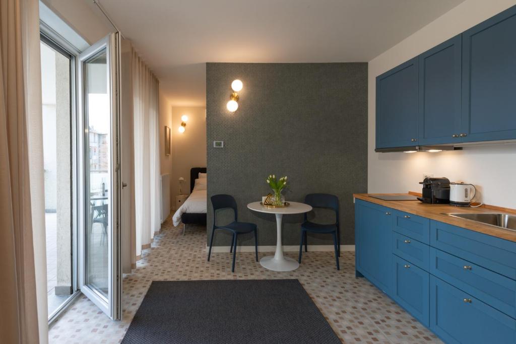 a kitchen with blue cabinets and a table with chairs at Marcello's Como Lake - Camerlata in Como